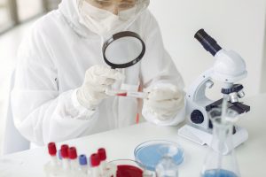 Scientist in coverall clothing is examining coronavirus sample in a laboratory