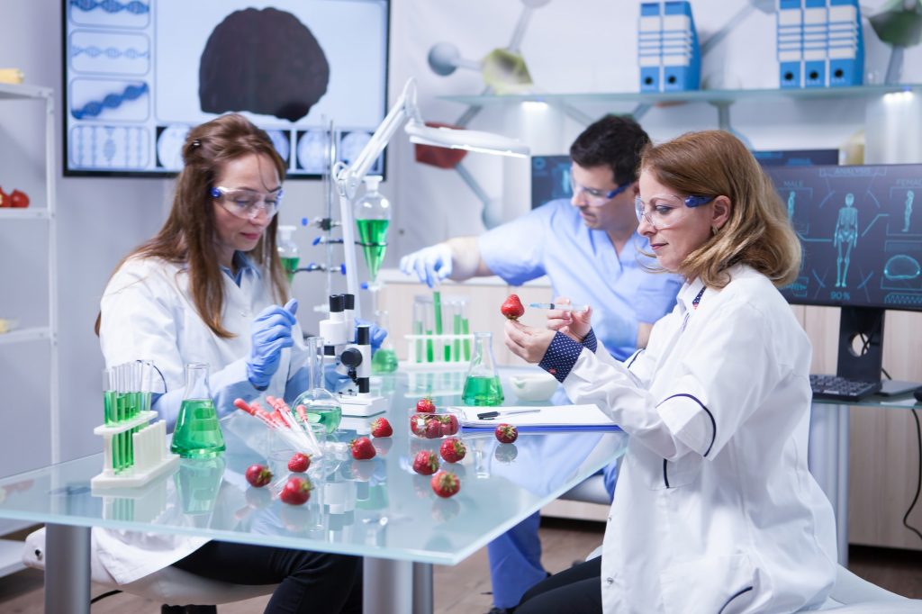 Caucasian woman with protection glasses doing scientific test on strawberries